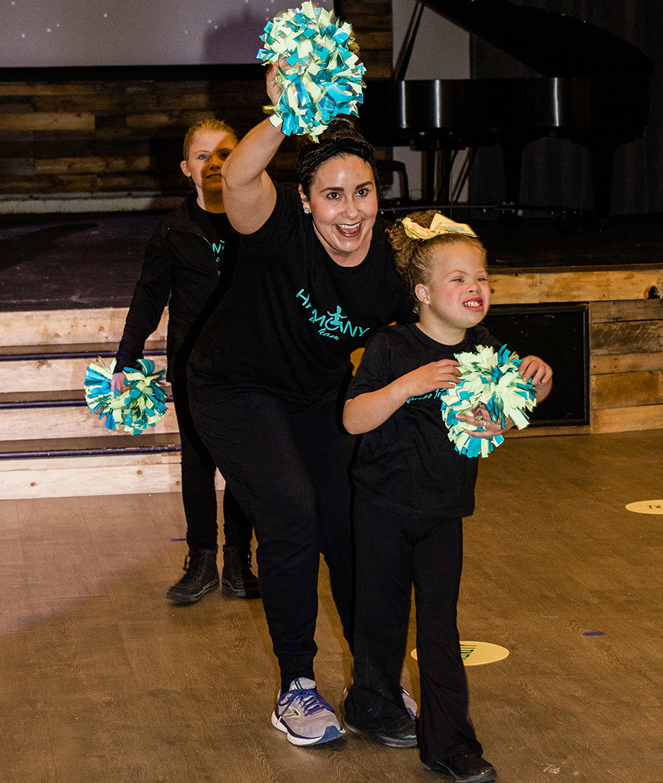 Instructor smiling with a girl holding pom poms