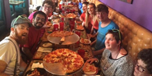People eating pizza at a long table