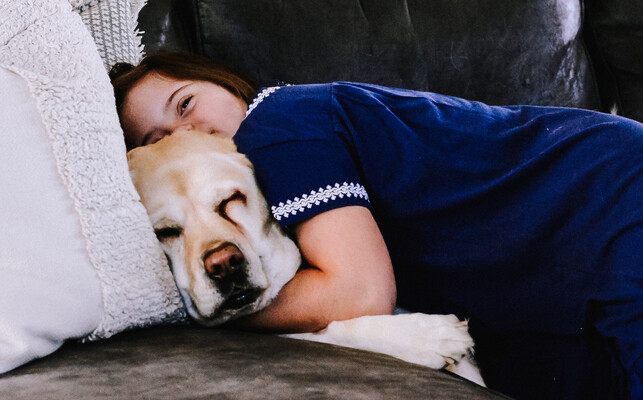Girl and dog laying together on the couch