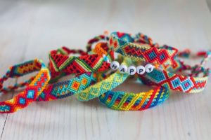 Multicolored woven bracelets, one with "happy" beaded across the front