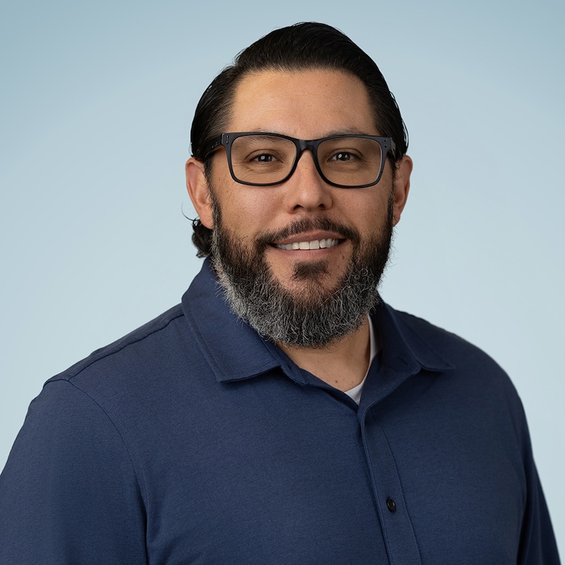 Man is glasses and dark brown hair with a beard smiling