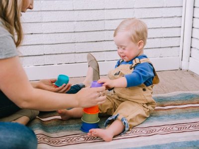 A baby boy playing with stacking cups with his therapist.